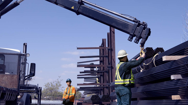 Two construction workers piling up beams
