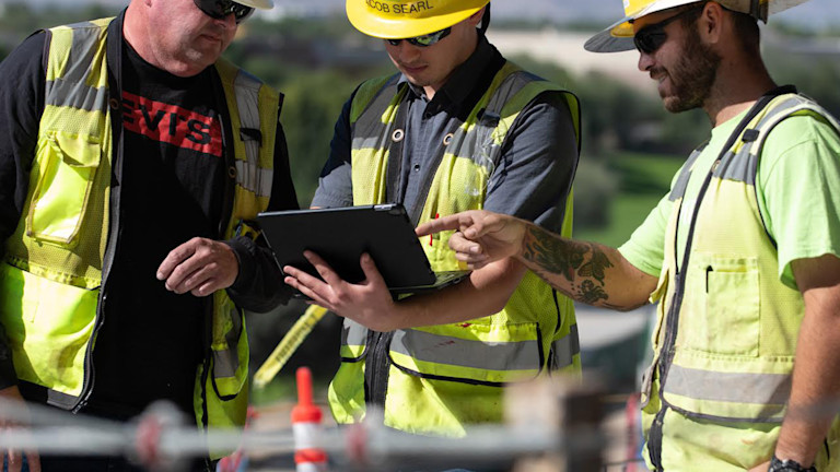 A group of men wearing yellow hard hats and vests