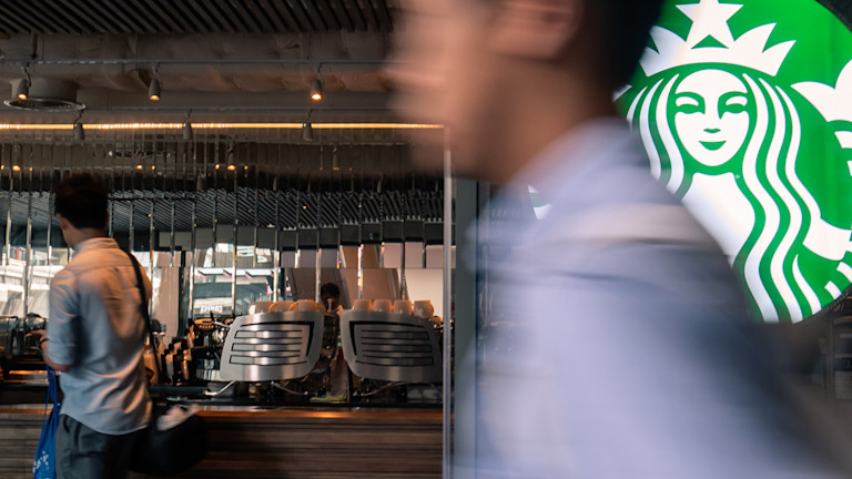 A man walking in front of a starbucks logo